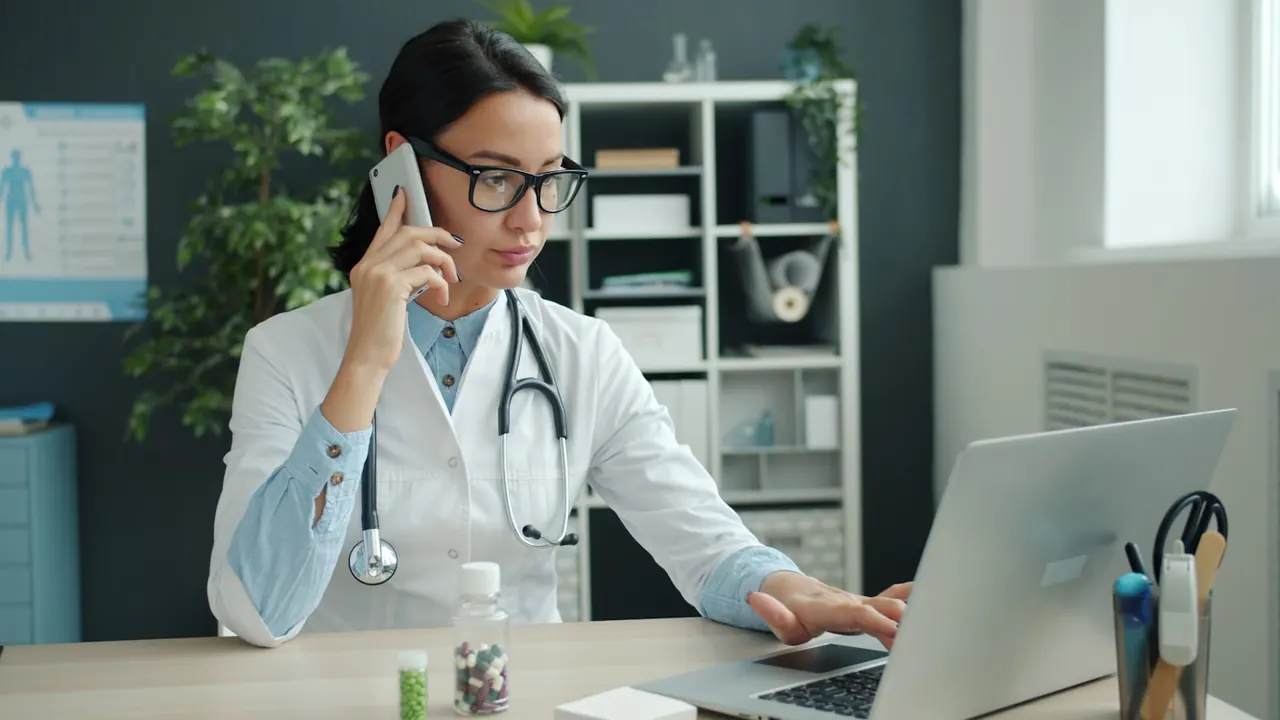 Clinician taking a phone call while working at a laptop in a practice office