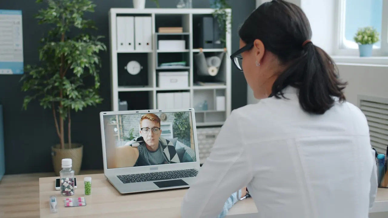 Clinician speaking with a patient over a video call on a laptop