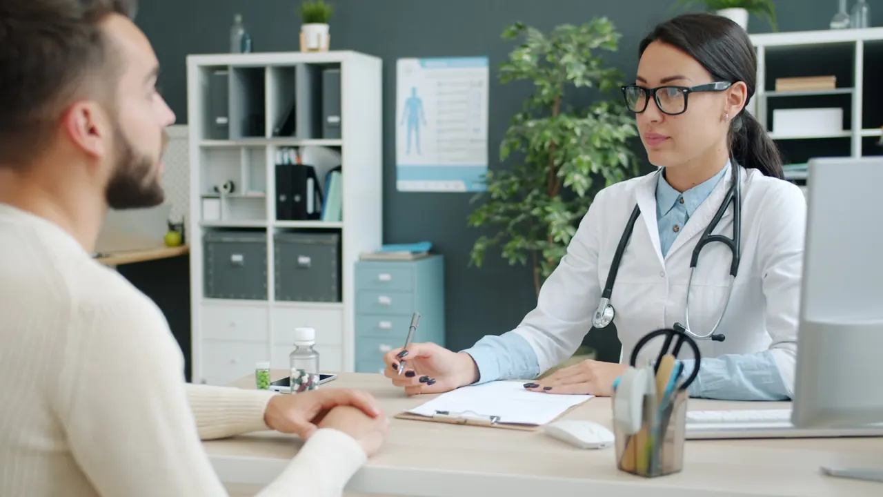 Clinician talking with a patient across a desk during a consultation